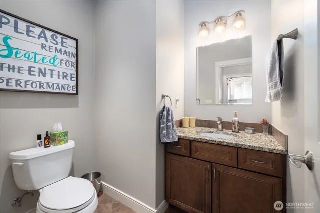 a bathroom with a granite countertop toilet sink and mirror