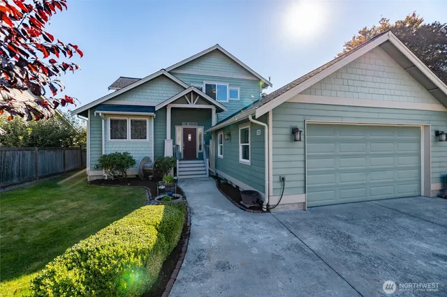 a view of a house with a yard plants and large tree