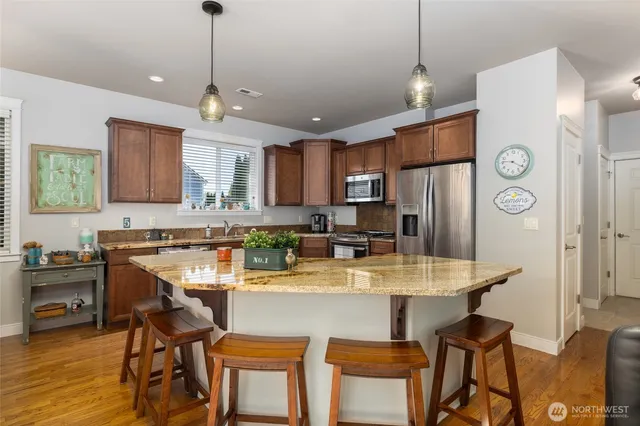 a kitchen with stainless steel appliances granite countertop a dining table chairs refrigerator and microwave
