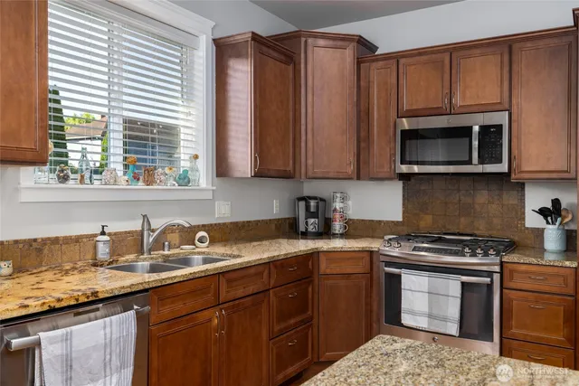 a kitchen with granite countertop a sink stove and microwave