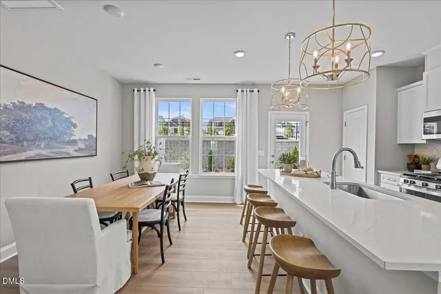a dining room with wooden floor a chandelier a wooden table and chairs