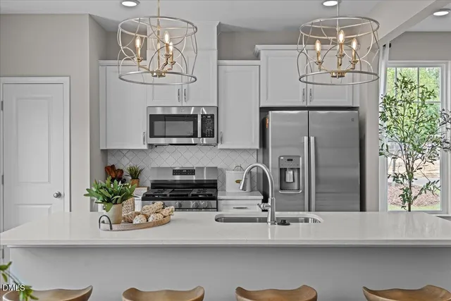 a kitchen with stainless steel appliances granite countertop a refrigerator a stove a microwave oven with a dining table and chairs