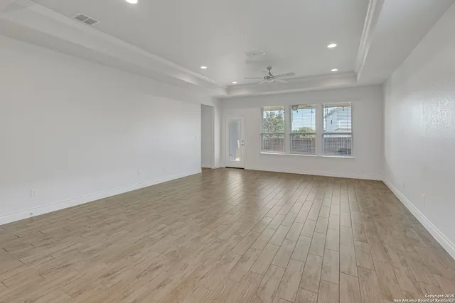 an empty room with wooden floor and windows