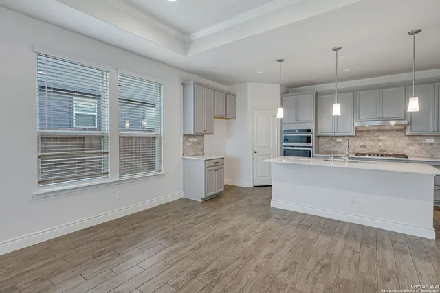 a large white kitchen with kitchen island a sink stainless steel appliances and cabinets