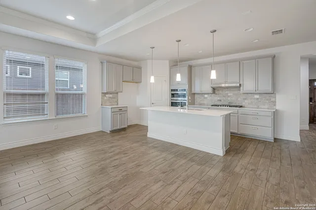 a large white kitchen with kitchen island a island wooden cabinets and stainless steel appliances