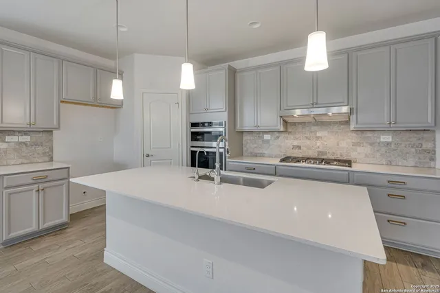 a kitchen with kitchen island a counter top space a sink stainless steel appliances and cabinets