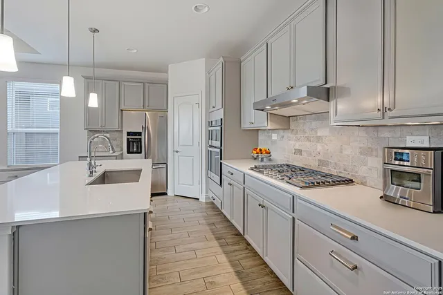 a kitchen with stainless steel appliances a stove a sink and white cabinets