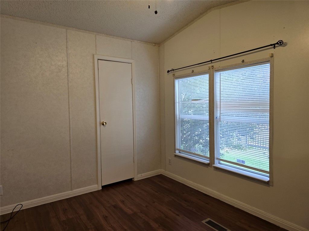 7628 Northview Lane Austin, TX 78724 - Photo 11 of 19 Spare room with a decorative wall, dark wood finished floors, a textured ceiling, and lofted ceiling
