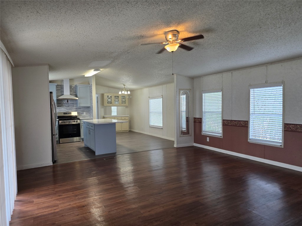 7628 Northview Lane Austin, TX 78724 - Photo 19 of 19 Kitchen with stainless steel appliances, wall chimney exhaust hood, open floor plan, light countertops, and dark wood-type flooring