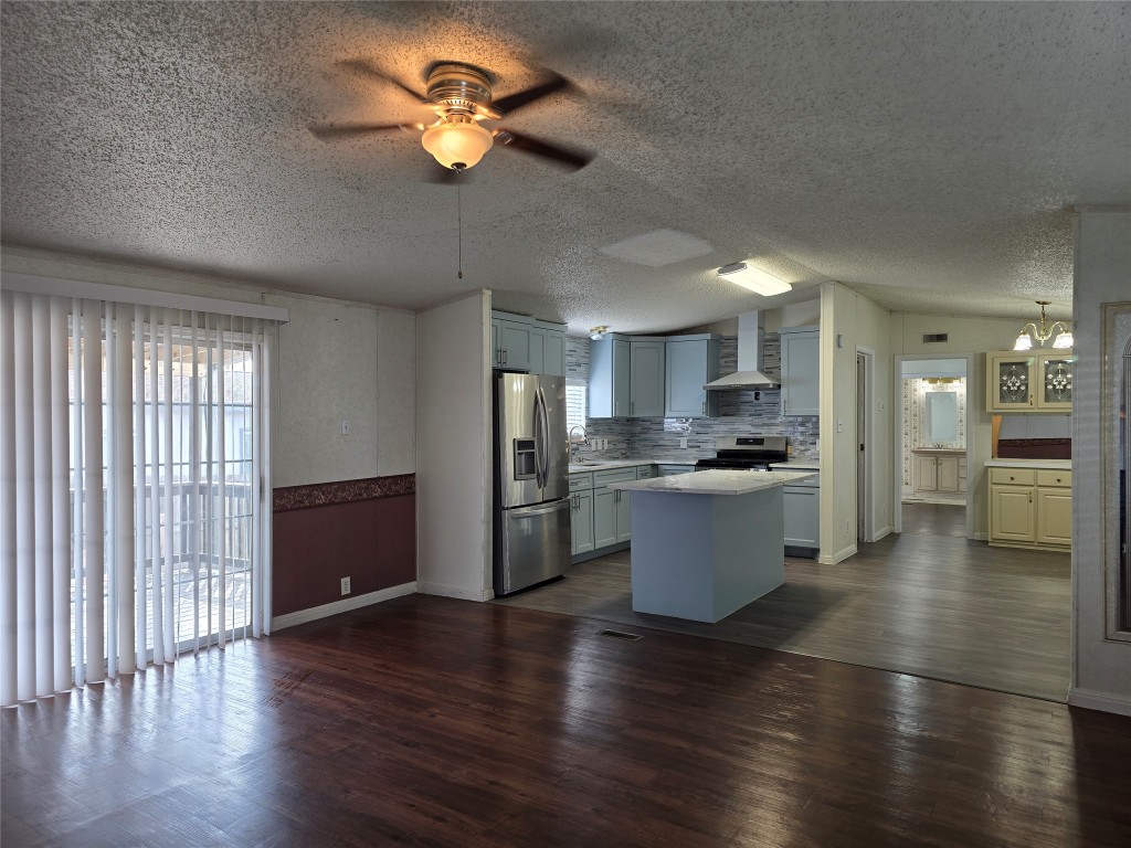 7628 Northview Lane Austin, TX 78724 - Photo 4 of 19 Kitchen with a center island, appliances with stainless steel finishes, wall chimney exhaust hood, ceiling fan, and vaulted ceiling