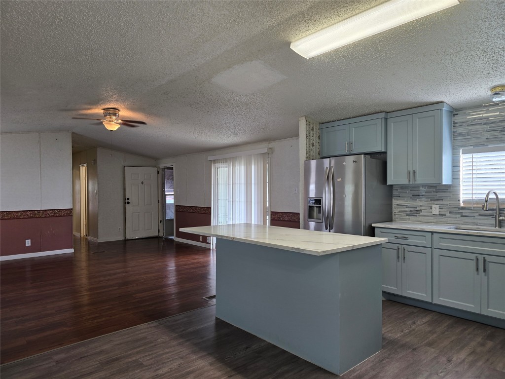 7628 Northview Lane Austin, TX 78724 - Photo 5 of 19 Kitchen featuring a center island, stainless steel fridge with ice dispenser, dark wood finished floors, plenty of natural light, and a textured ceiling