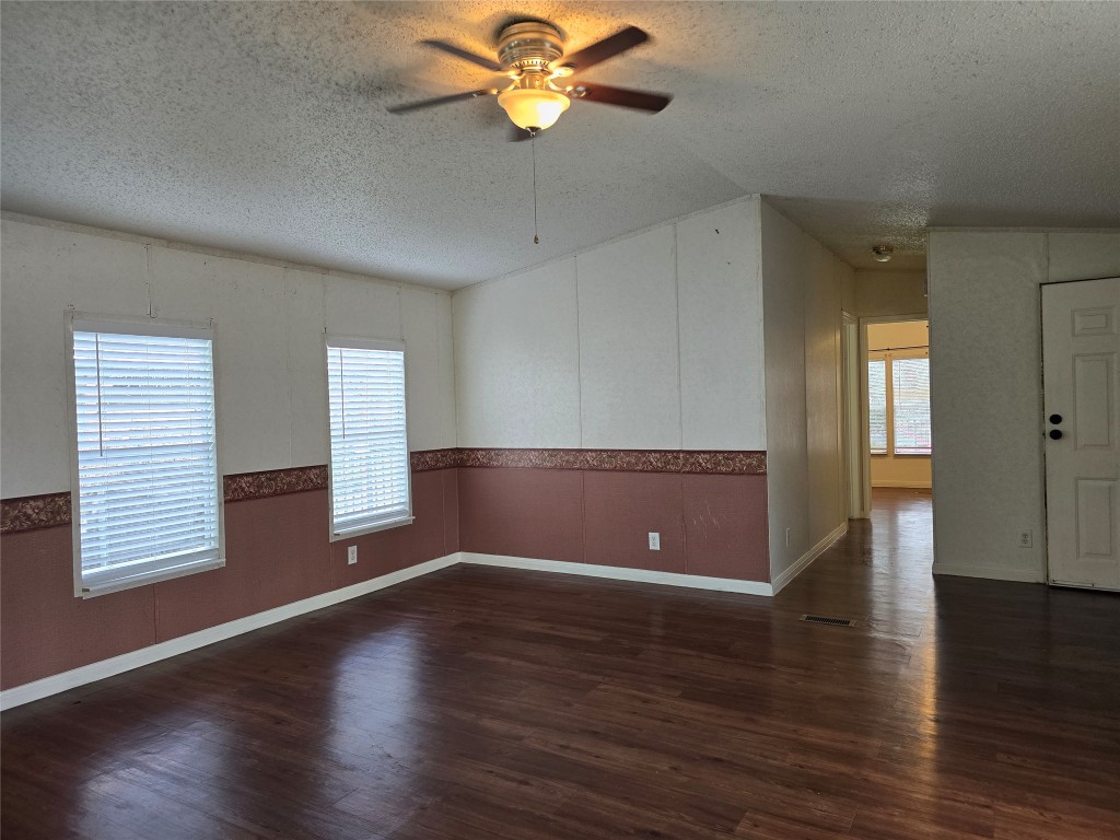 7628 Northview Lane Austin, TX 78724 - Photo 9 of 19 Empty room featuring dark wood-type flooring, a textured ceiling, wainscoting, and ceiling fan