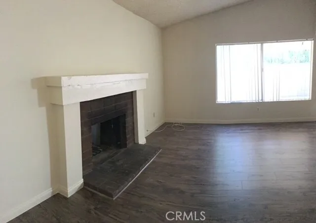 an empty room with wooden floor fireplace and windows
