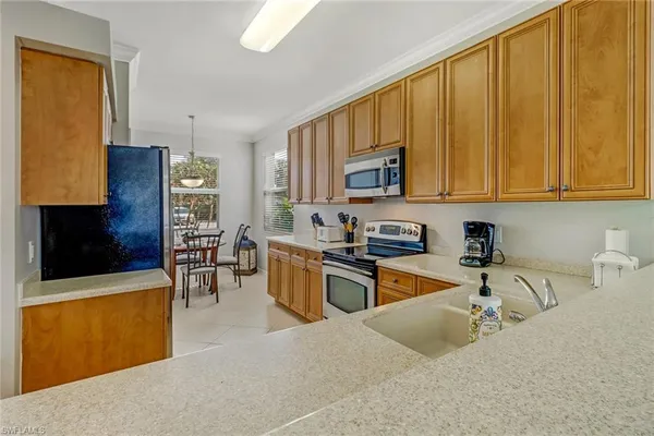 a kitchen with stainless steel appliances granite countertop a stove top oven a sink a dining table and chairs with wooden floor