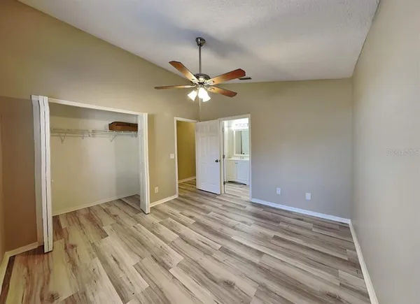 a view of an empty room with window and a ceiling fan