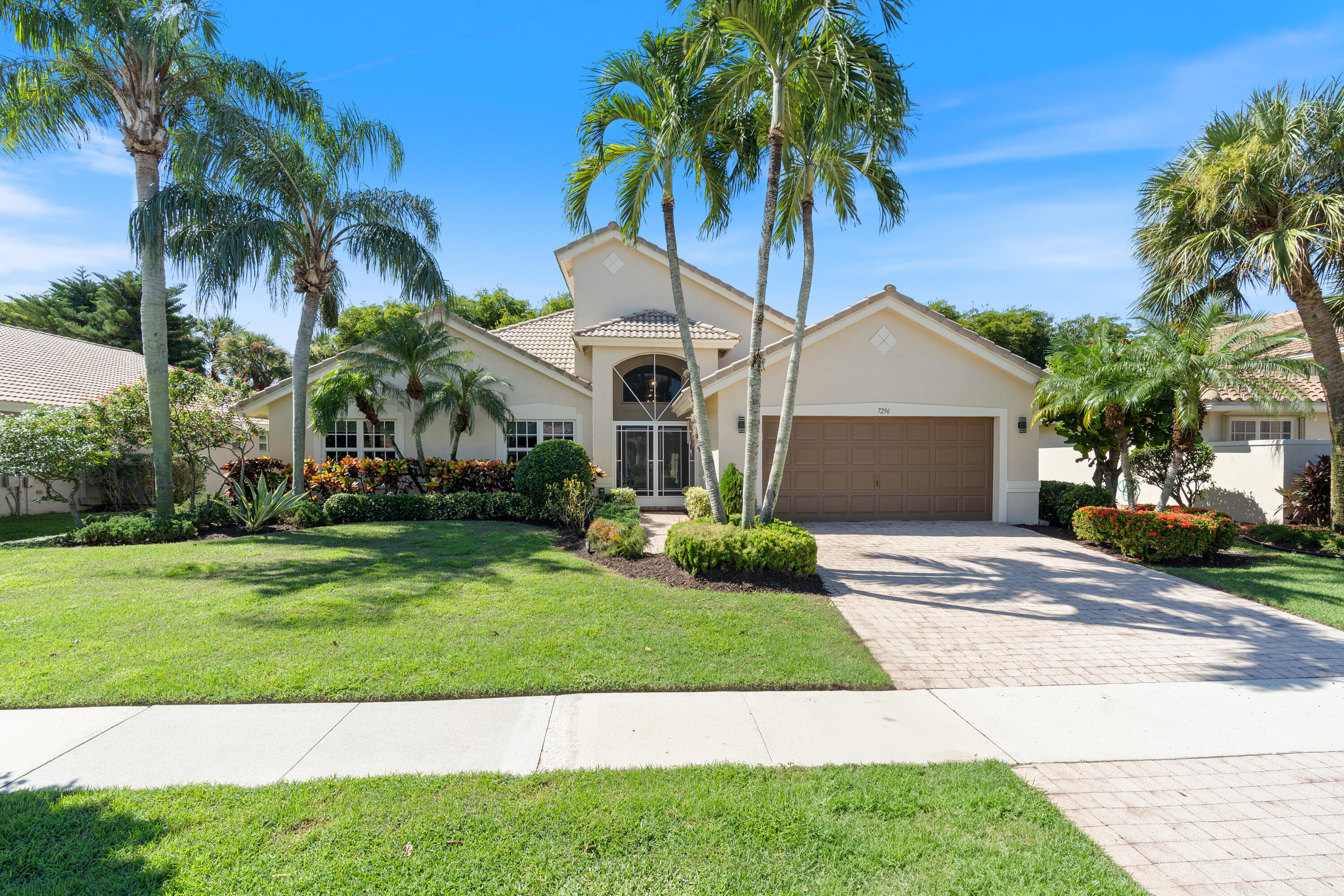 a front view of a house with a garden and palm trees