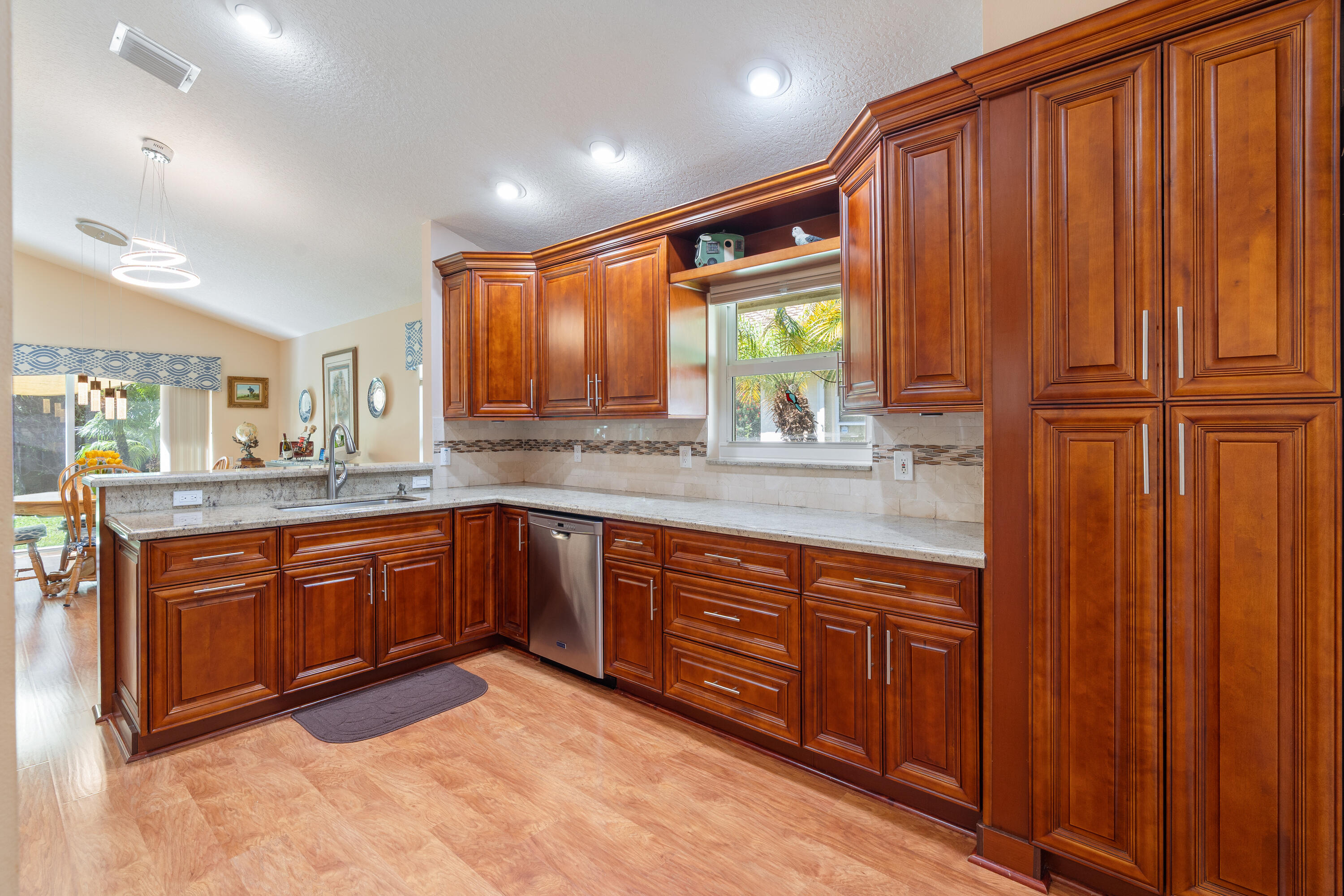 7296 Falls Road East Boynton Beach, FL 33437 - Photo 8 of 25 a large kitchen with kitchen island granite countertop wooden cabinets a sink a window and stainless steel appliances