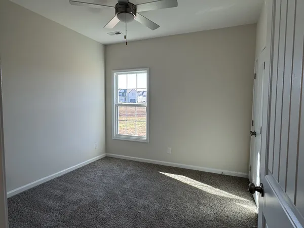 an empty room with a window and ceiling fan
