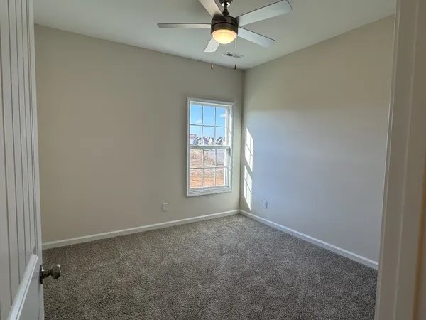 an empty room with a window and a fan