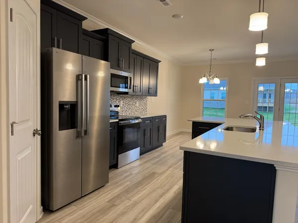 a kitchen with kitchen island a counter top space a refrigerator and a sink