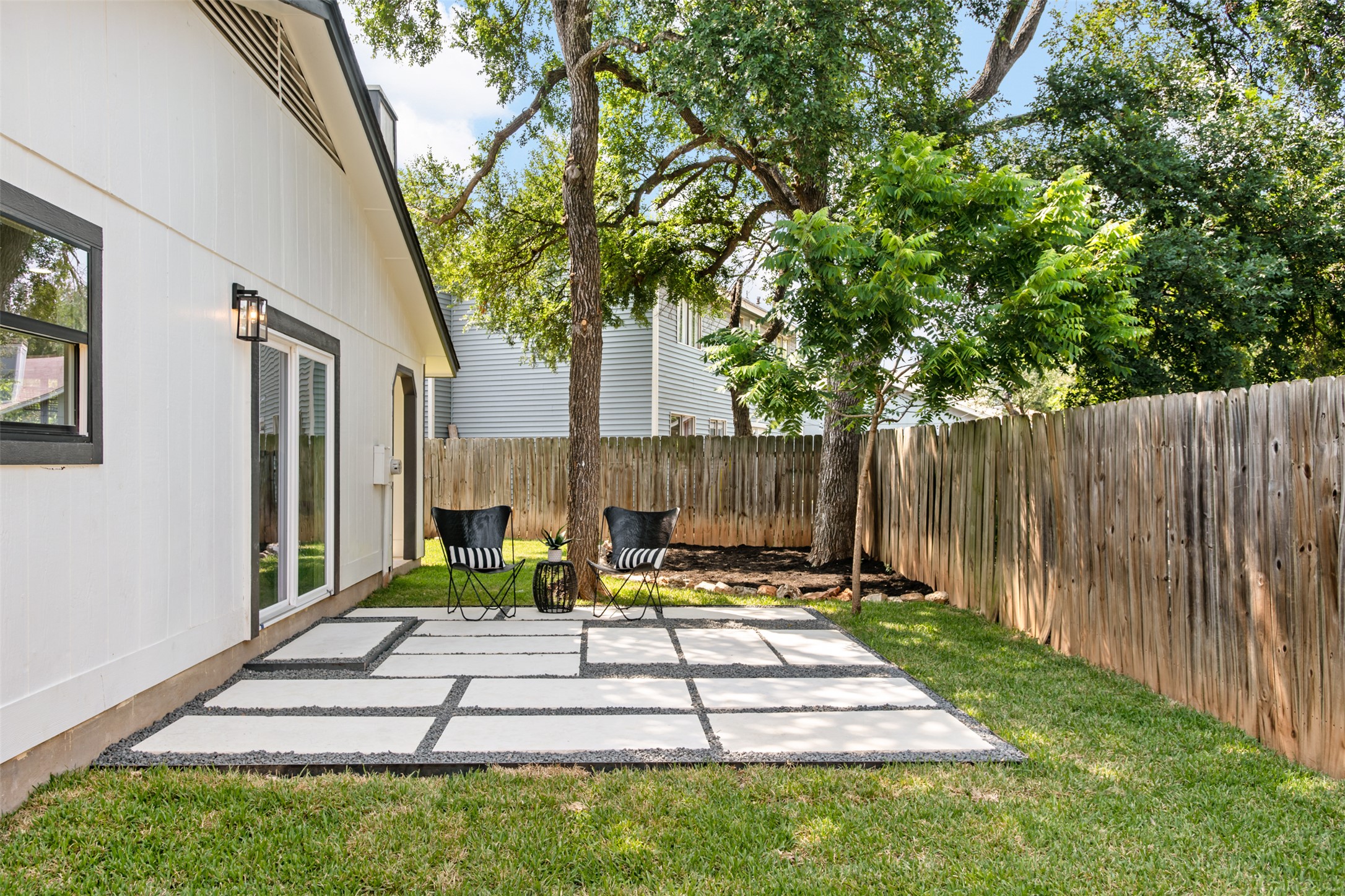 7604 Islander Drive Austin, TX 78749 - Photo 36 of 38 A private backyard oasis features a geometric paver patio and ample green space, perfect for outdoor enjoyment.