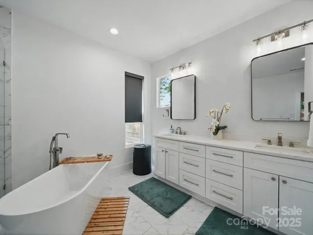 a bathroom with a double vanity sink mirror and bathtub