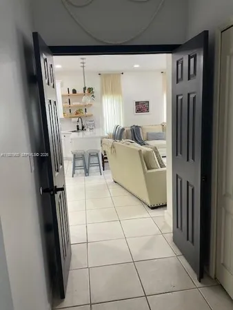 a living room with furniture a refrigerator a table and a large window