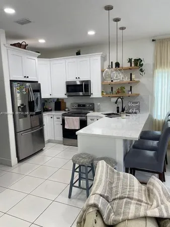 a kitchen with stainless steel appliances kitchen island granite countertop a sink a stove a refrigerator cabinets and chairs