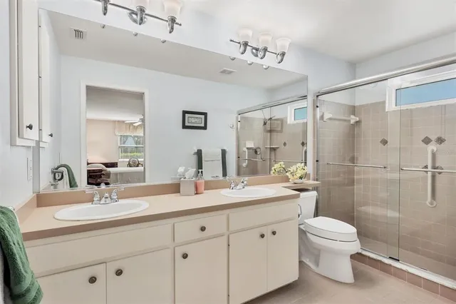 a bathroom with a double vanity sink toilet mirror and shower