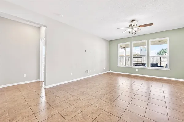a view of an empty room with a window and chandelier fan