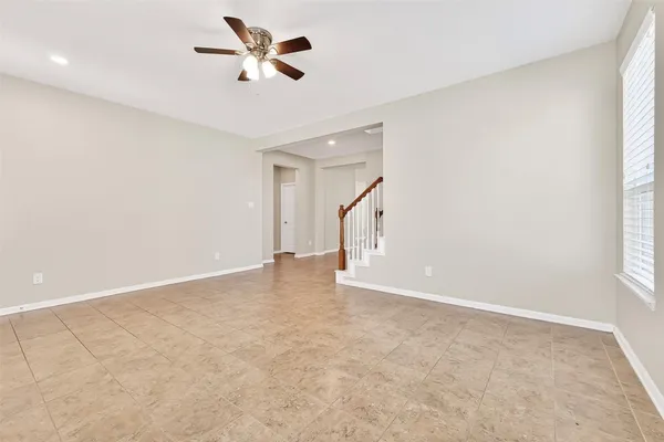 an empty room with chandelier fan and windows