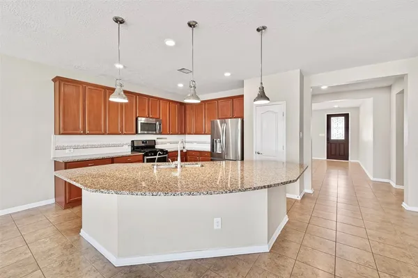 a large kitchen with kitchen island a large center island a stove cabinets and a counter top space