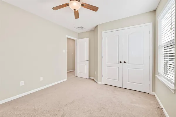 an empty room with windows and fan