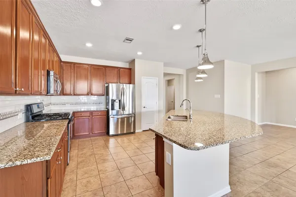 a kitchen with stainless steel appliances granite countertop a sink a stove and a wooden cabinets