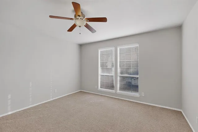 an empty room with a ceiling fan and window