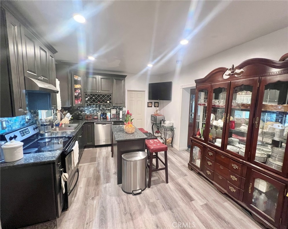 1166 El Mirage Road Adelanto, CA 92301 - Photo 12 of 21 a kitchen with stainless steel appliances kitchen island granite countertop a stove a refrigerator a dining table and chairs with wooden floor