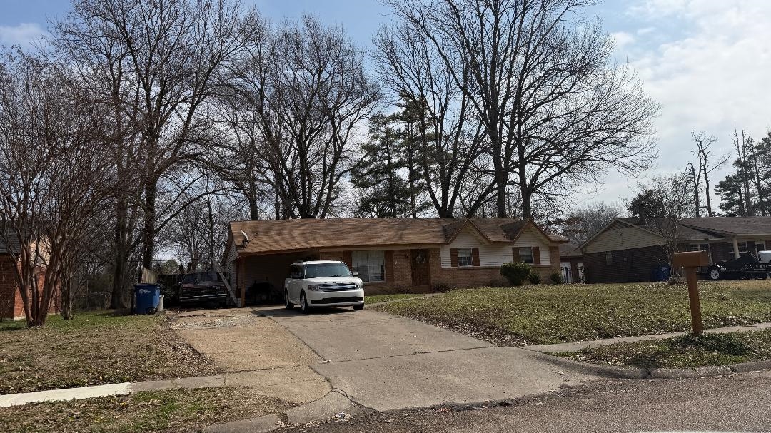 Single story home with brick siding, driveway, and a front yard