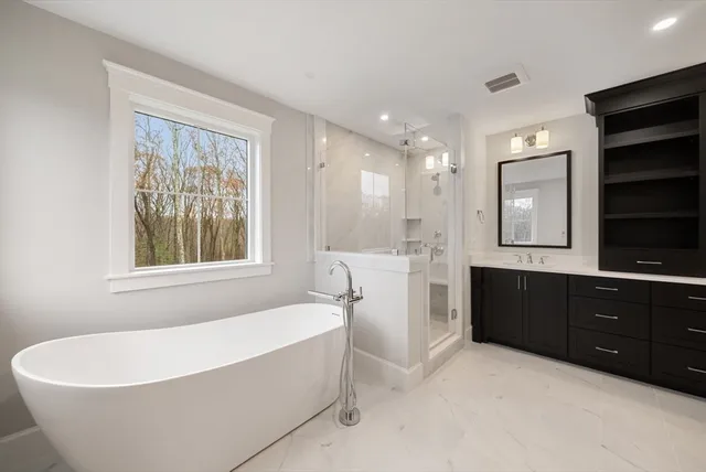a spacious bathroom with a bathtub double sink and mirror