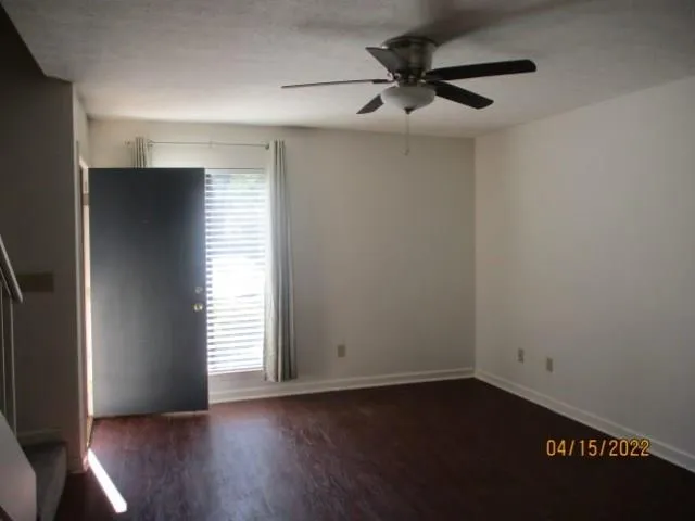 an empty room with wooden floor closet and windows