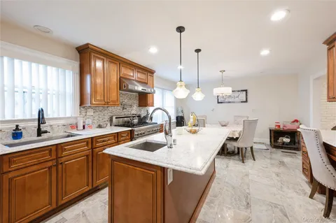a kitchen with kitchen island granite countertop a sink a counter top space appliances and cabinets