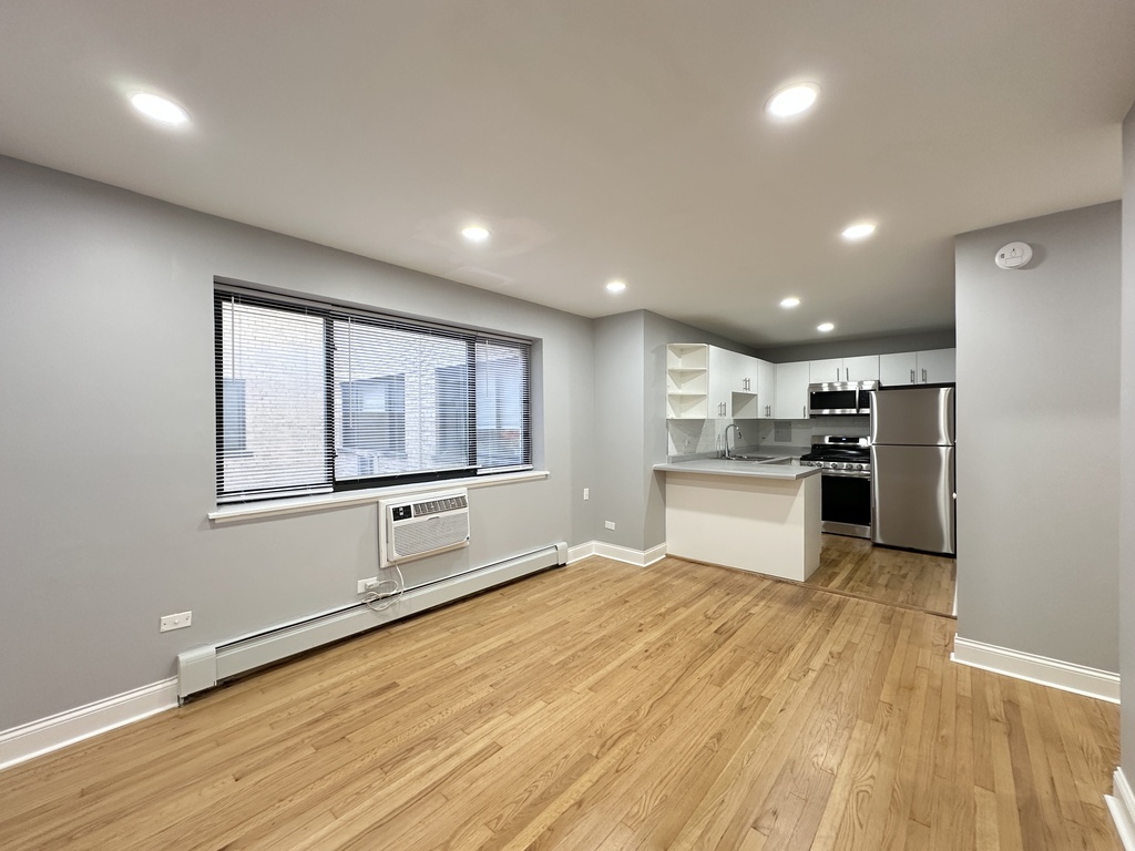 6954 North Sheridan Road, Unit 312 Chicago, IL 60626 - Photo 11 of 21 a large white kitchen with stainless steel appliances granite countertop a stove a sink white cabinets and a large window