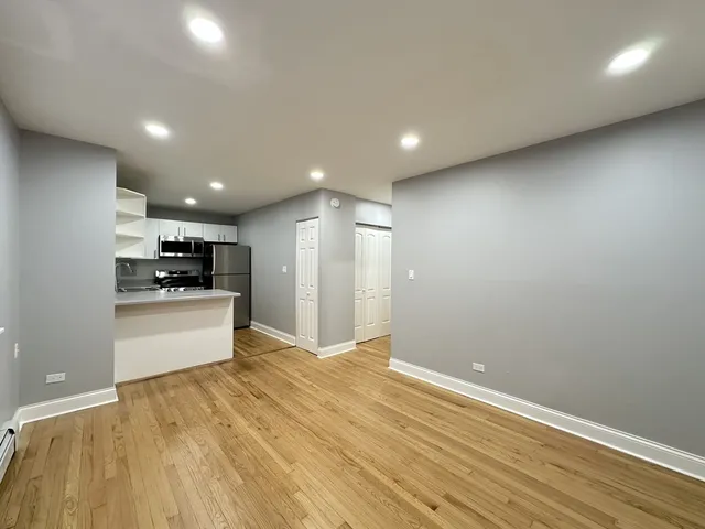 a view of kitchen with kitchen island a sink wooden floor and stainless steel appliances