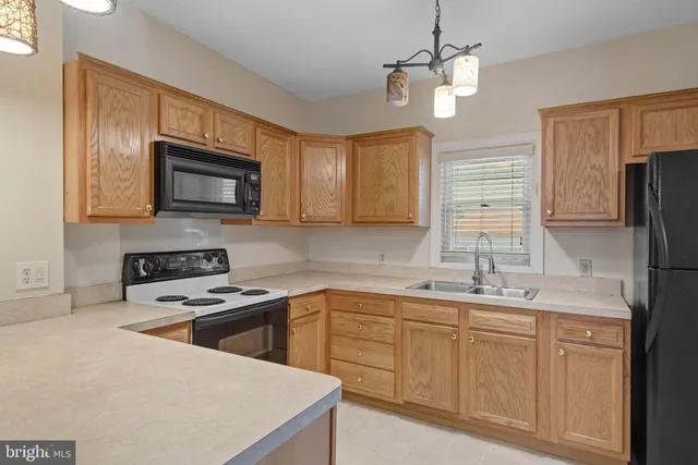 a kitchen with stainless steel appliances granite countertop a sink a stove a refrigerator cabinets and chairs