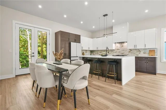 a kitchen with kitchen island granite countertop a stove a sink a refrigerator and white cabinets with wooden floor