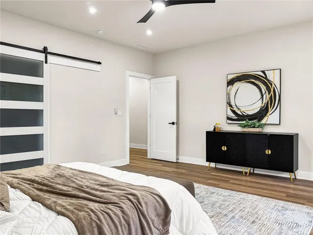 an empty room with wooden floor fan and windows