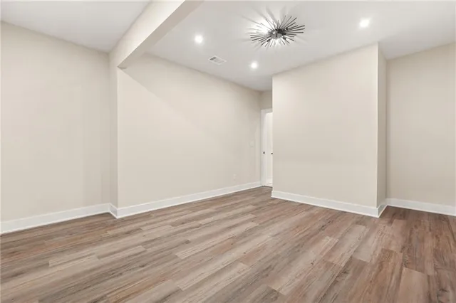 an empty room with wooden floor fan and windows