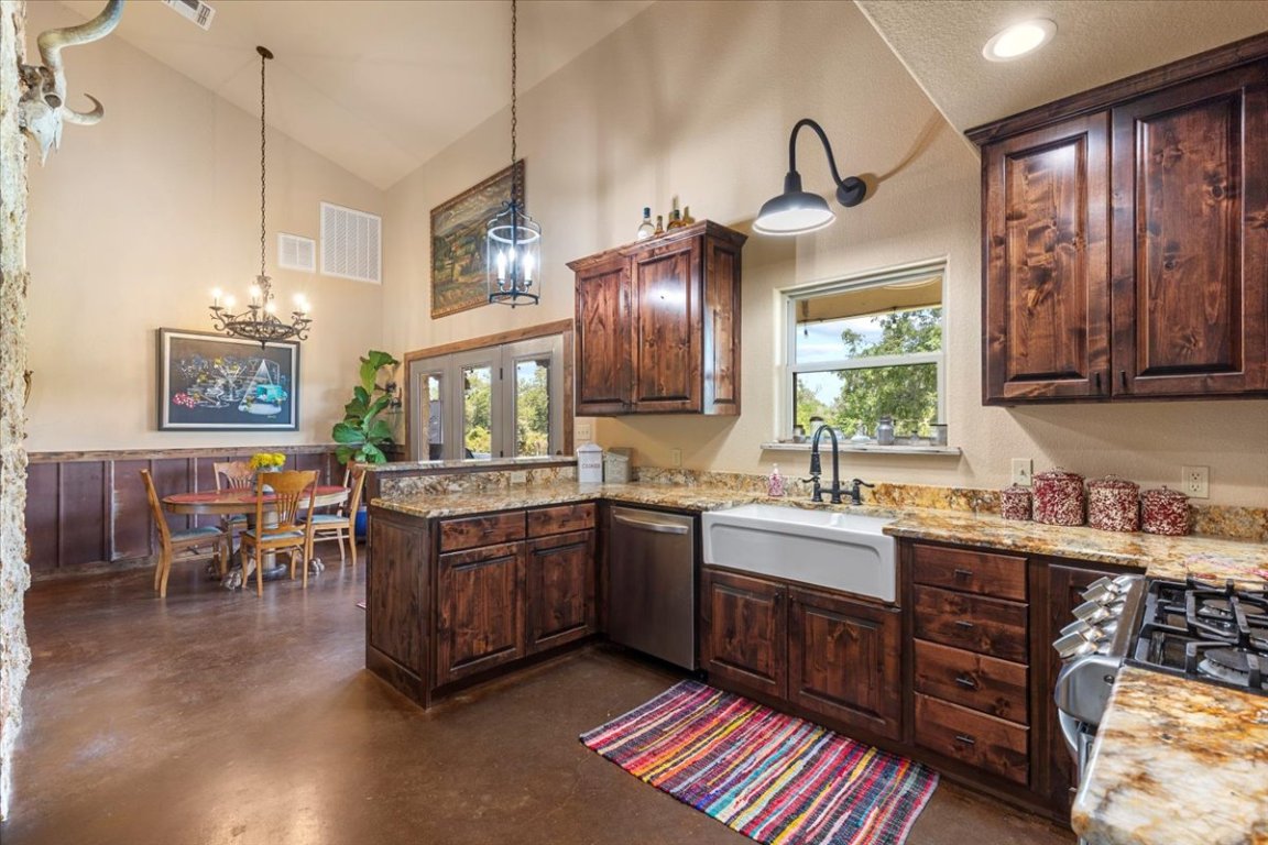 7835 Berger Road Schulenburg, TX 78956 - Photo 11 of 40 Kitchen featuring finished concrete floors, a peninsula, stainless steel dishwasher, light stone counters, and high vaulted ceiling
