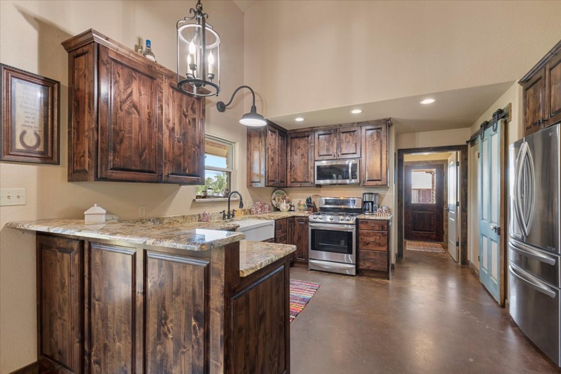 7835 Berger Road Schulenburg, TX 78956 - Photo 13 of 40 Kitchen with a barn door, appliances with stainless steel finishes, concrete flooring, a peninsula, and recessed lighting