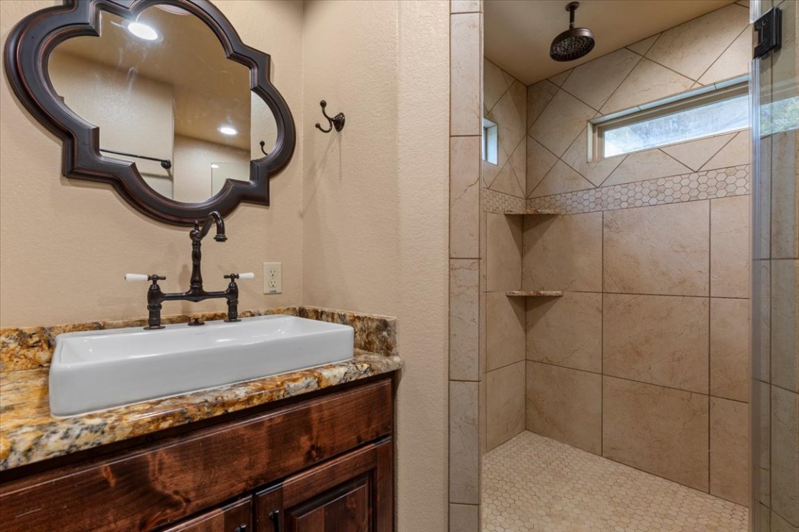 7835 Berger Road Schulenburg, TX 78956 - Photo 16 of 40 Full bathroom featuring a tile shower, vanity, and a textured wall