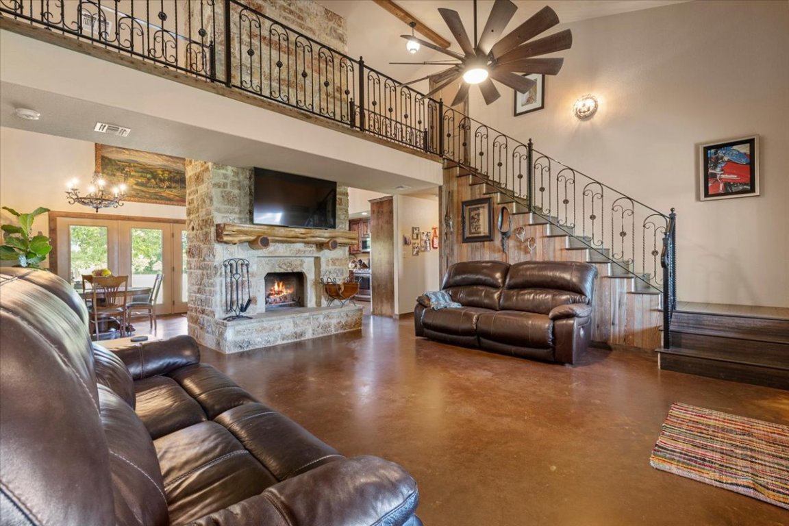 7835 Berger Road Schulenburg, TX 78956 - Photo 8 of 40 Living area with finished concrete flooring, stairway, a fireplace, a high ceiling, and accent wall on stairwell is wood from the Leneski homestead